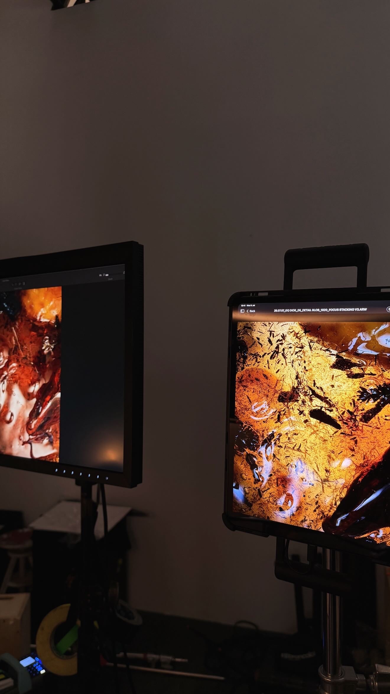 Two studio monitors display close studies of illuminated amber, oud and reflected Dior Sauvage Extrait details during the Milan shoot.