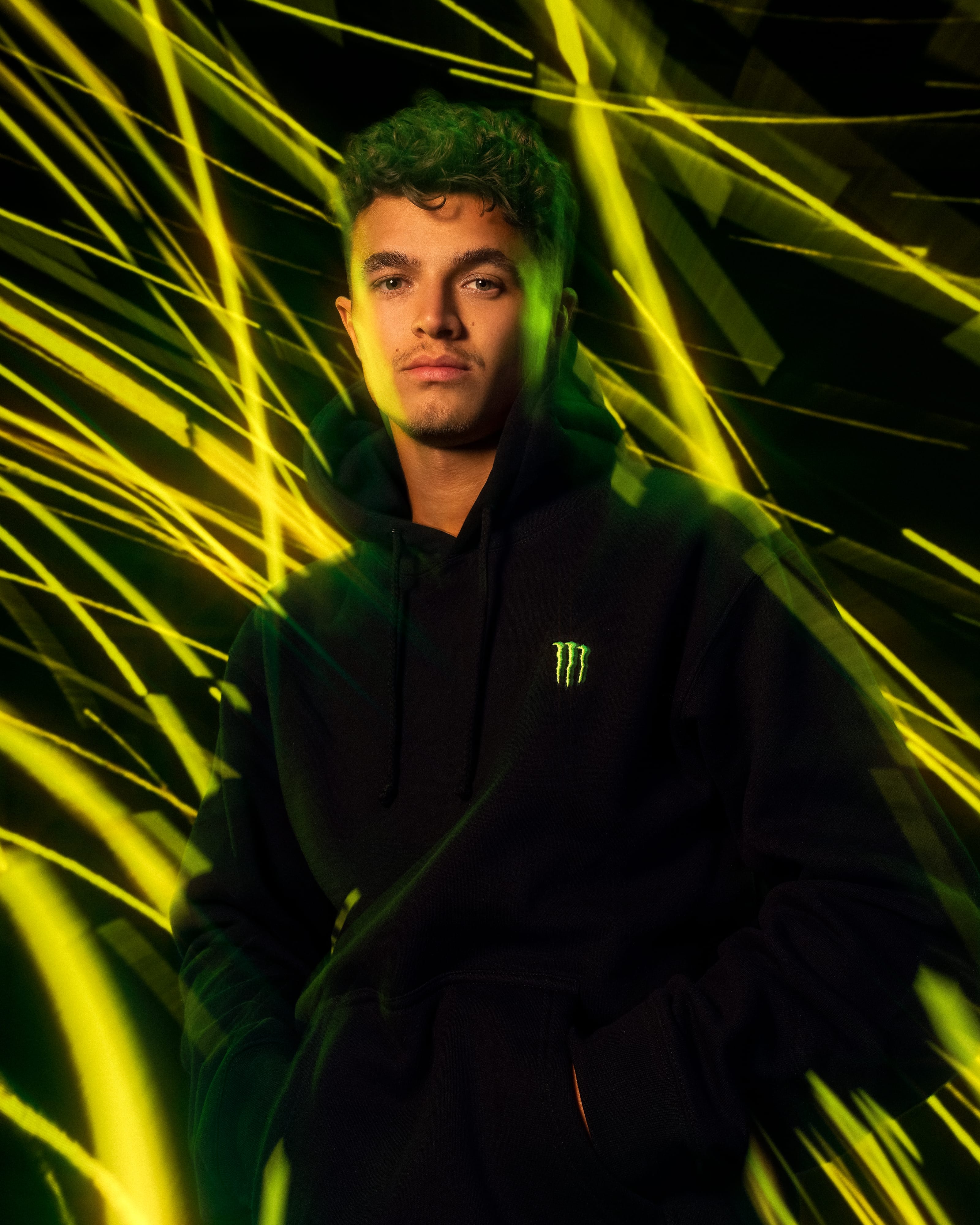 Lando Norris photographed by George Kroustallis amid yellow-and-green in-camera light trails for the Monster Energy global launch campaign.