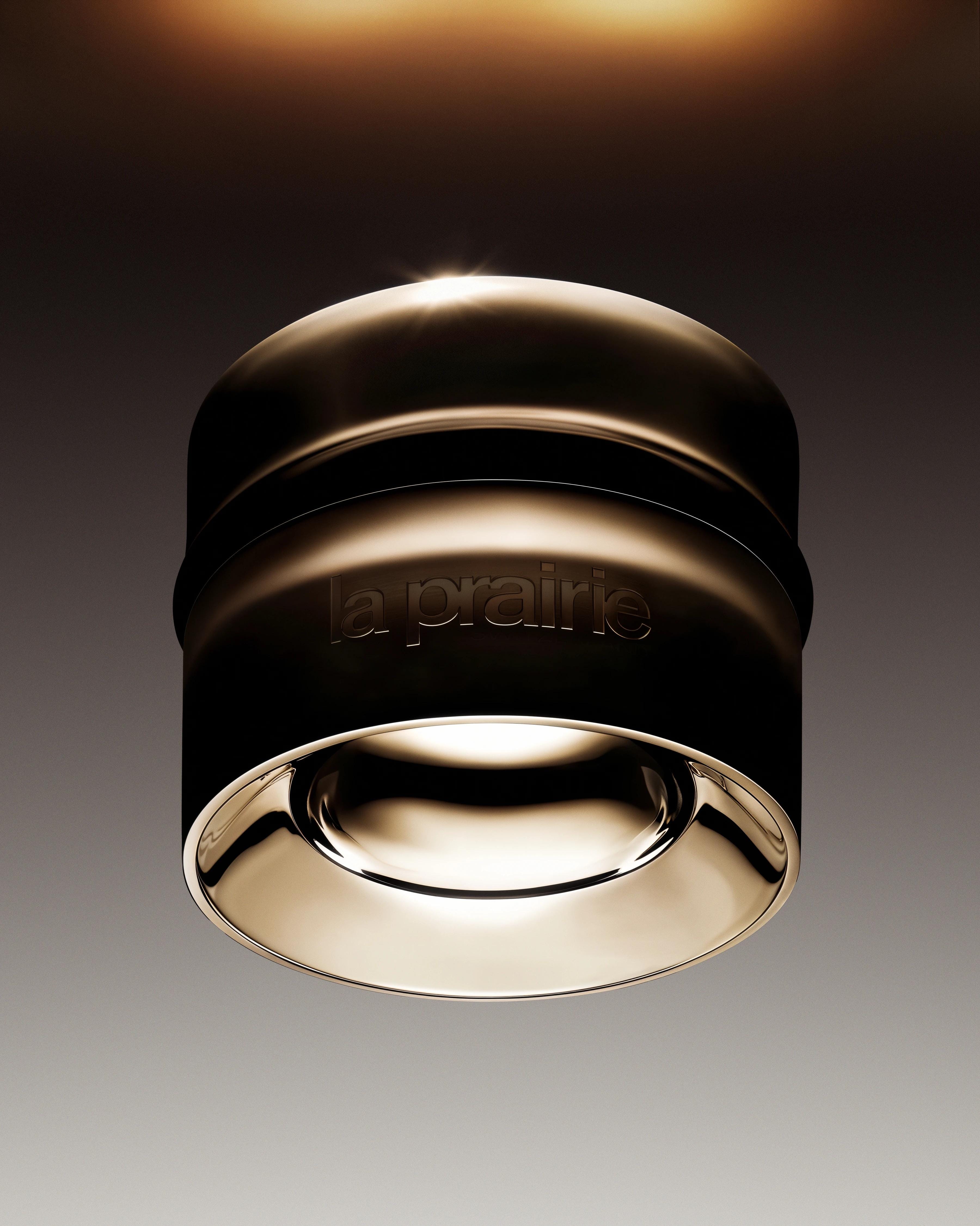 Black La Prairie skincare jar suspended beneath a narrow band of warm bronze light.