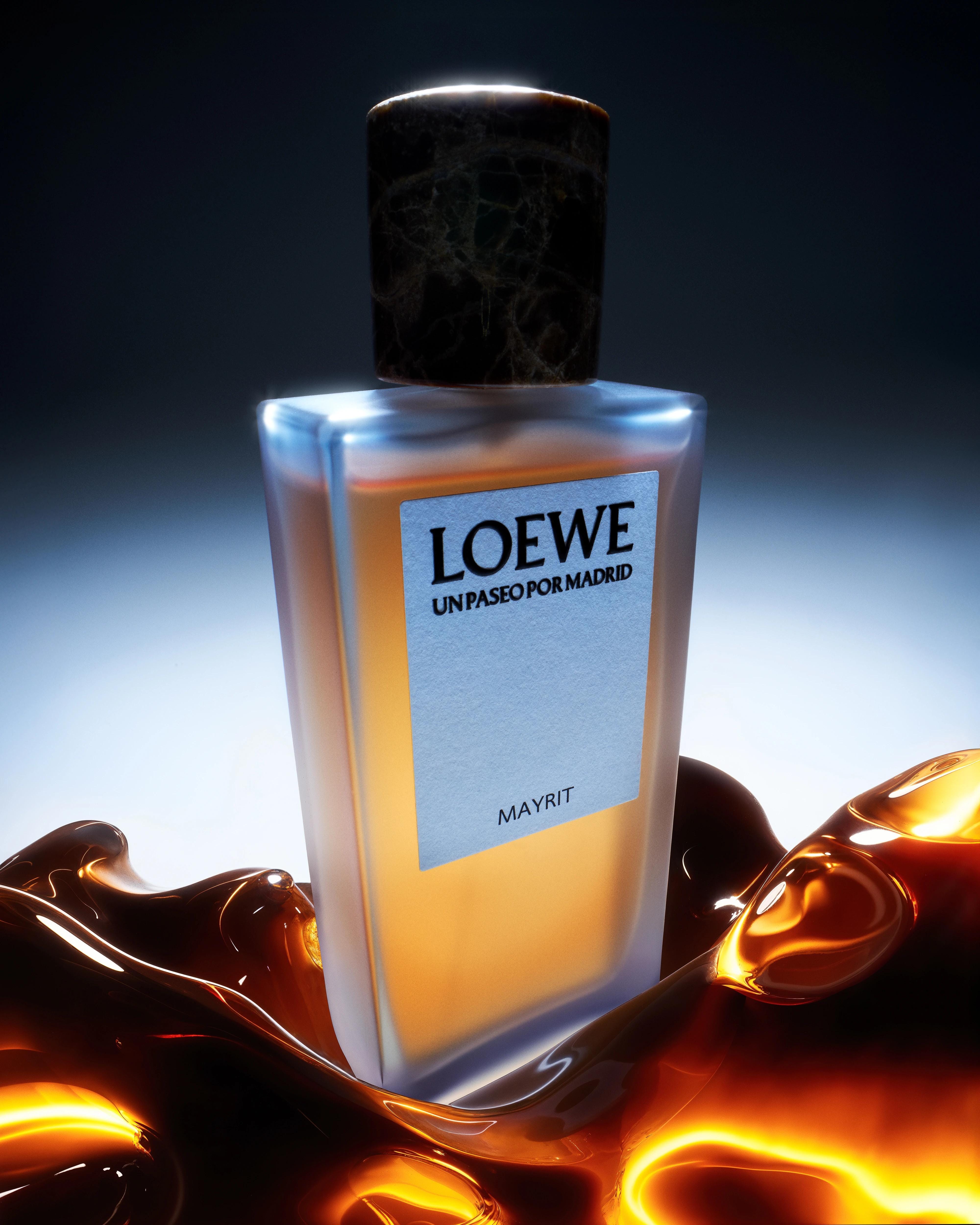 LOEWE Un Paseo por Madrid Mayrit perfume bottle surrounded by glossy amber forms under cool blue rim light.