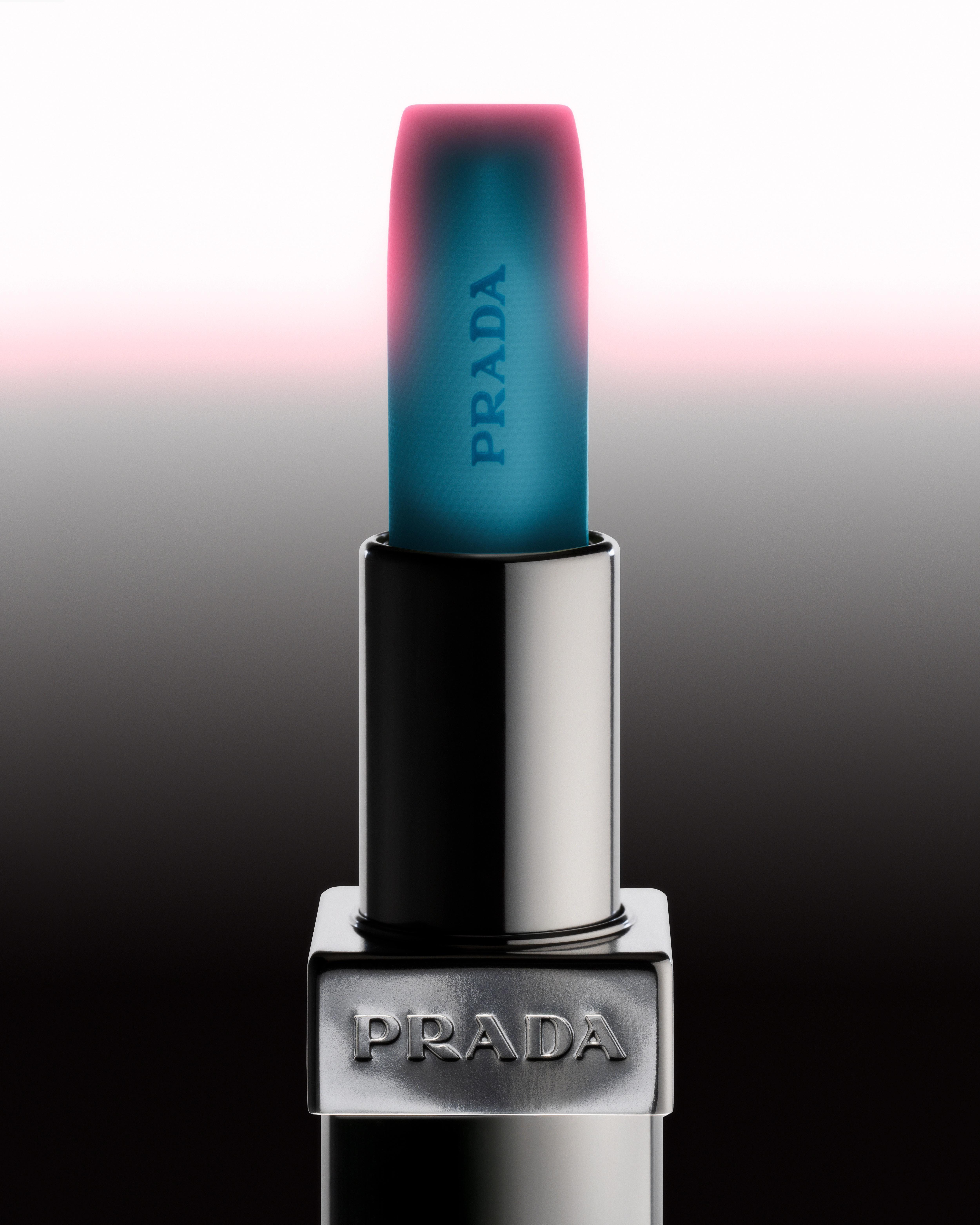 Prada Balm U001 Astral Pink standing in its silver case, with blue-green balm edged in pink against a white-to-black gradient.