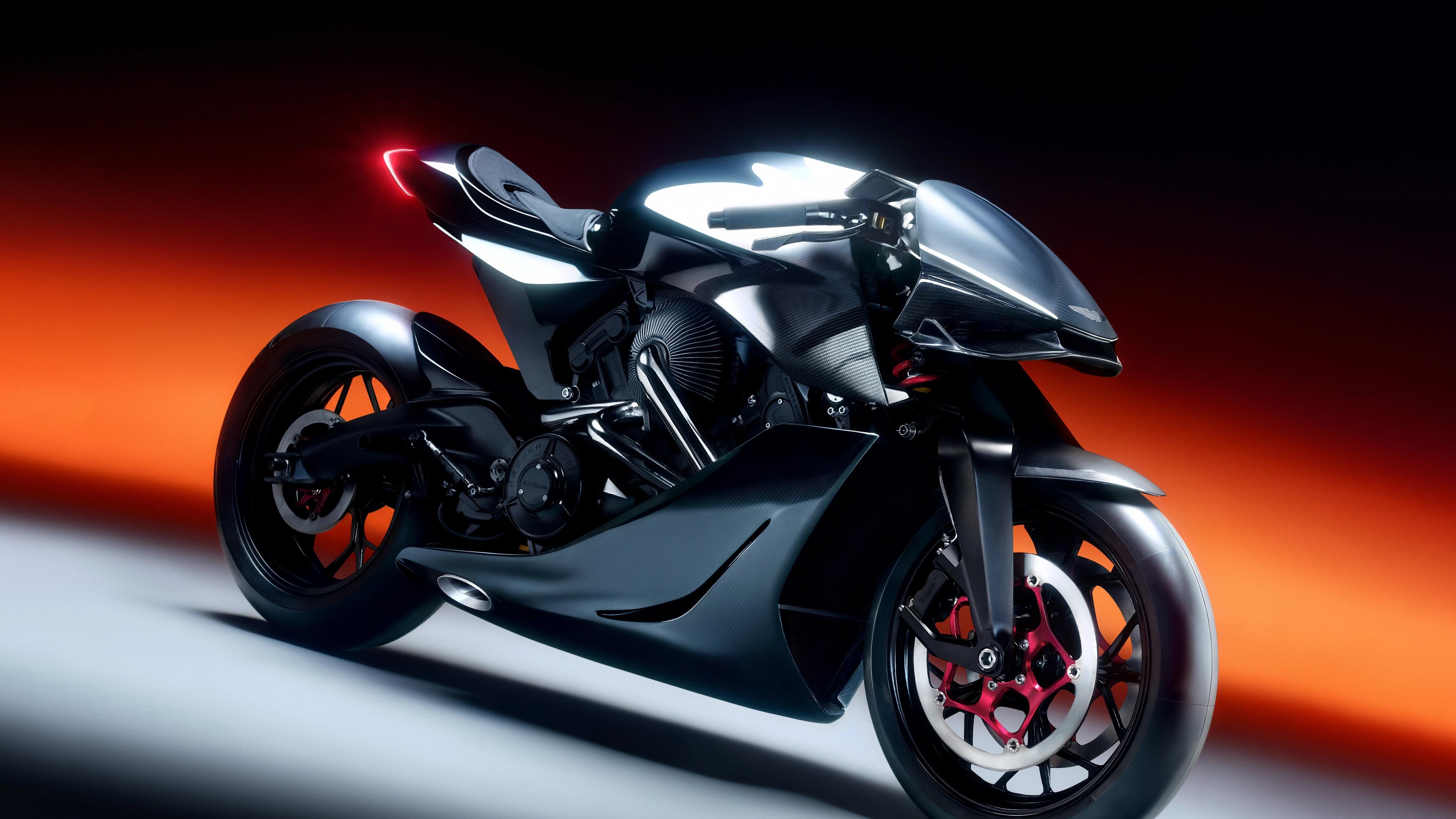 Black Aston Martin and Brough Superior AMB 001 motorcycle in three-quarter view against a red-orange light band.