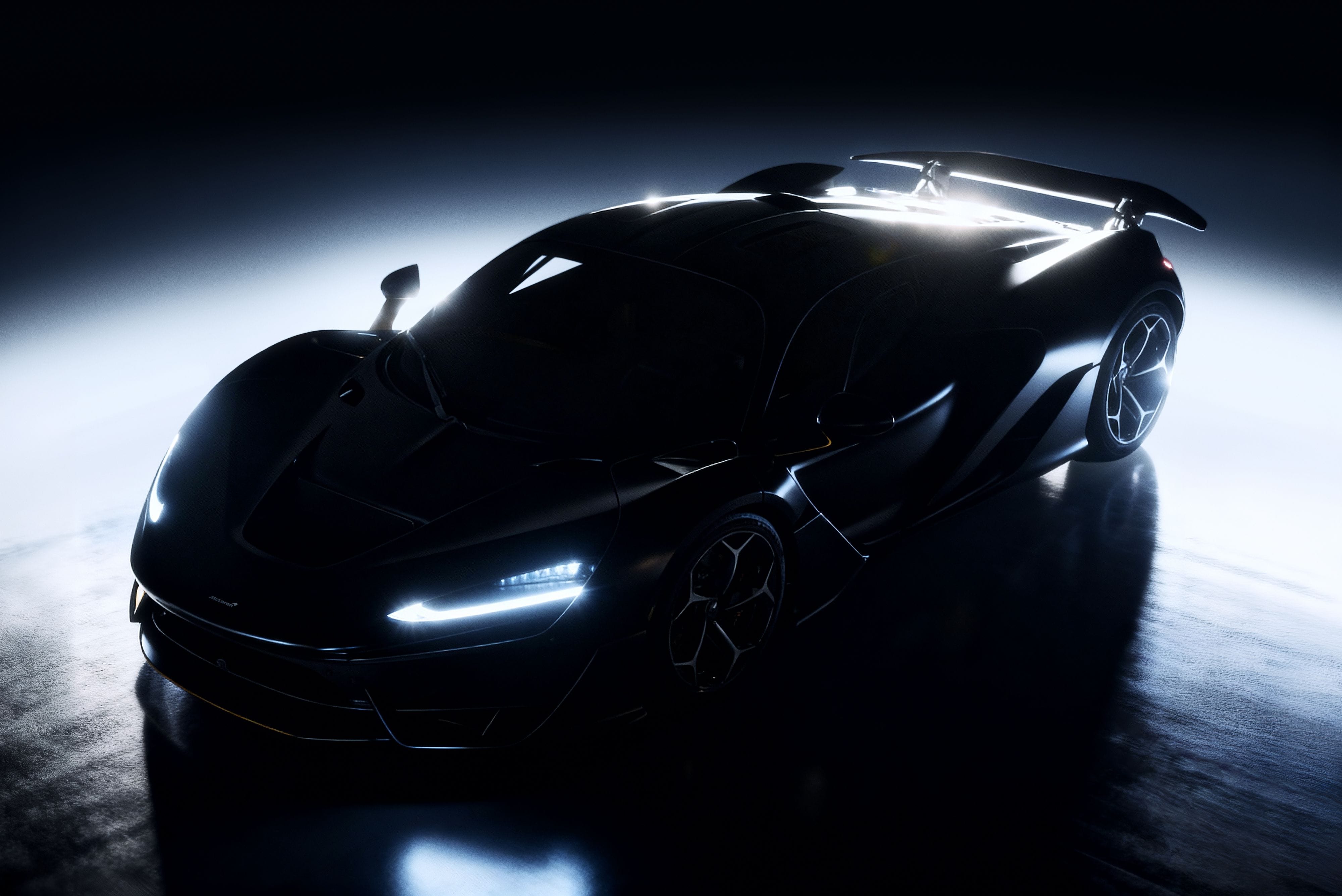 Dark front three-quarter view of a McLaren W1 with its headlights reflected across the studio floor.