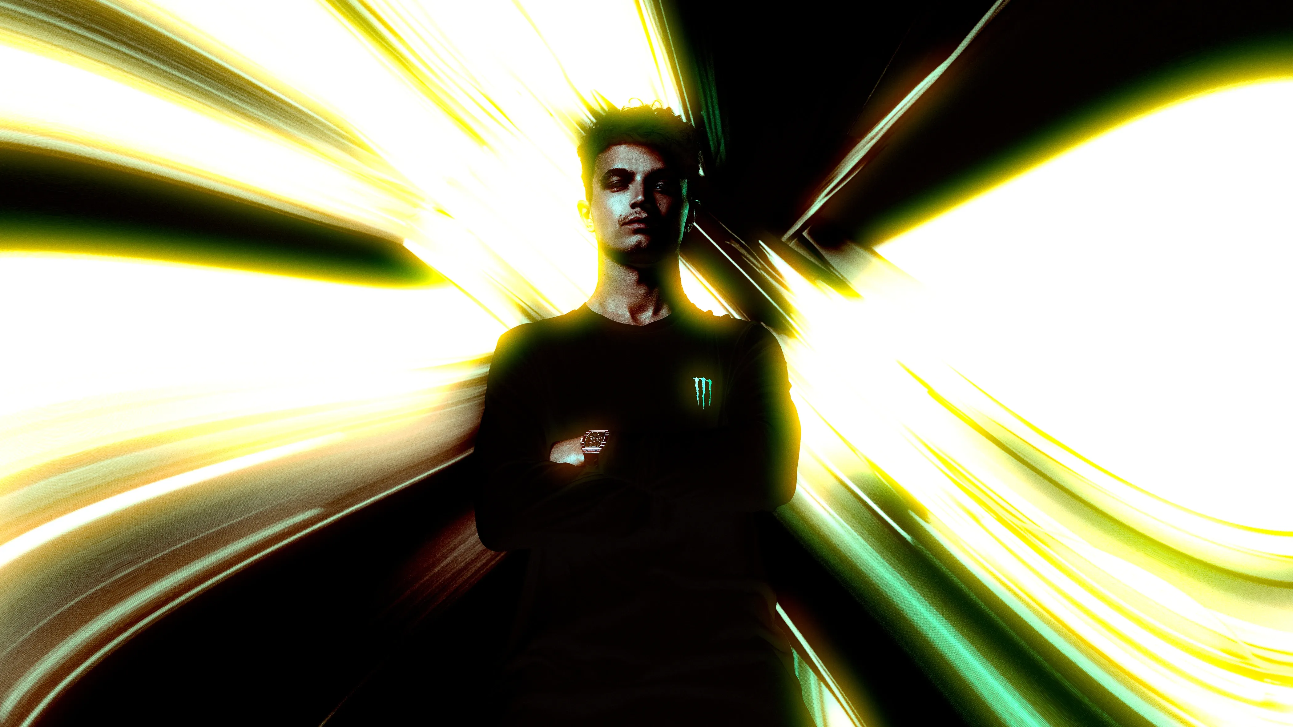 Lando Norris standing with folded arms inside radial yellow-green light trails created with an LED-volume backdrop and an in-camera zoom pull.