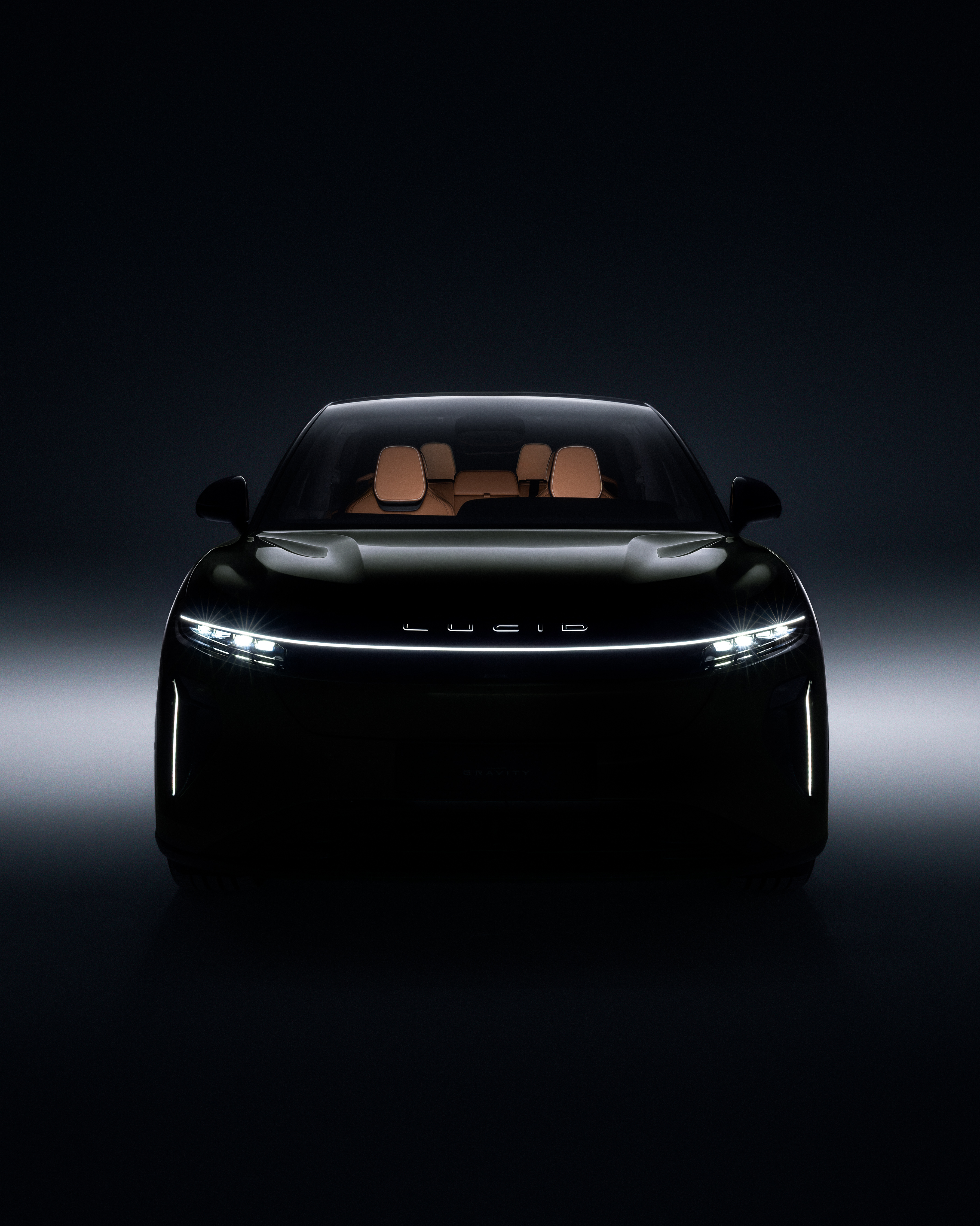 Final frontal photograph of the Lucid Gravity by George Kroustallis, emerging from a deep blue-black studio gradient with its illuminated front light signature.